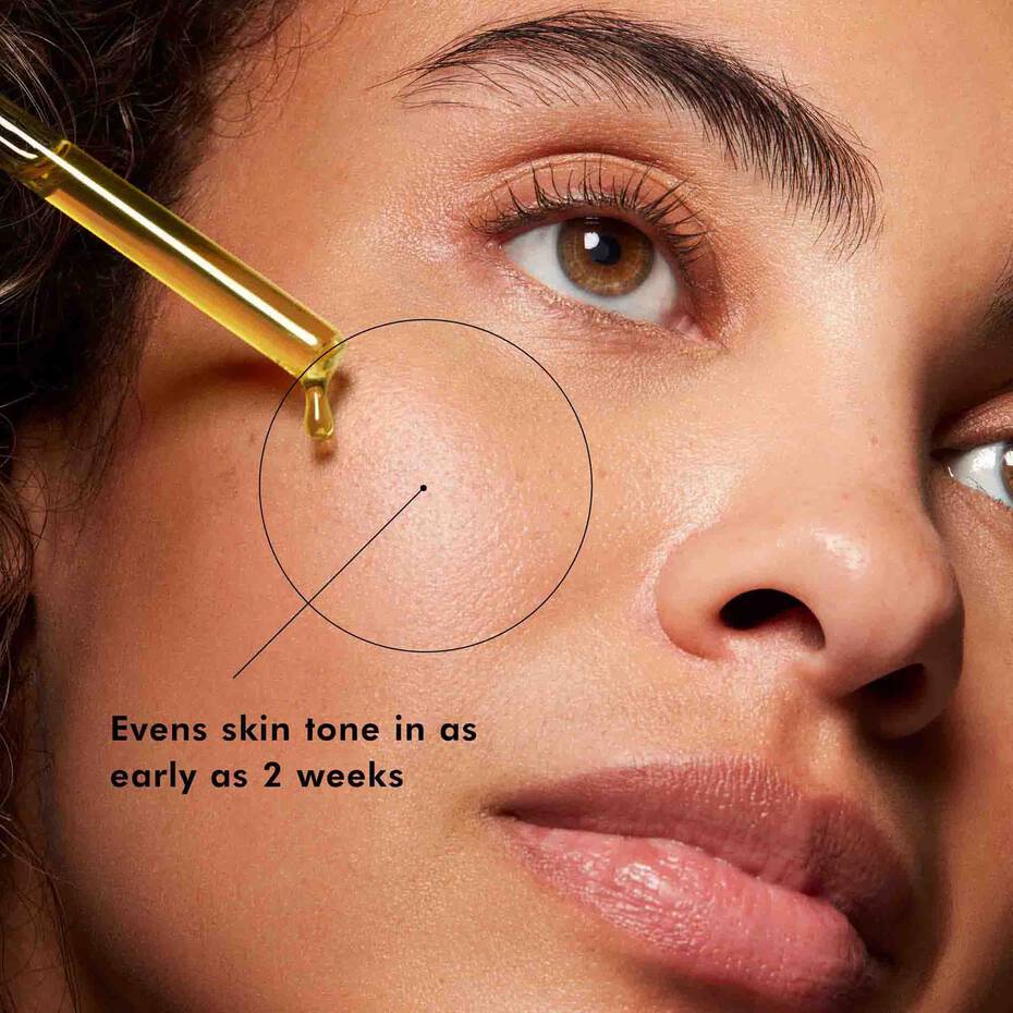 Close-up of a woman's face with a dropper applying a product, text indicating skin tone evenness.