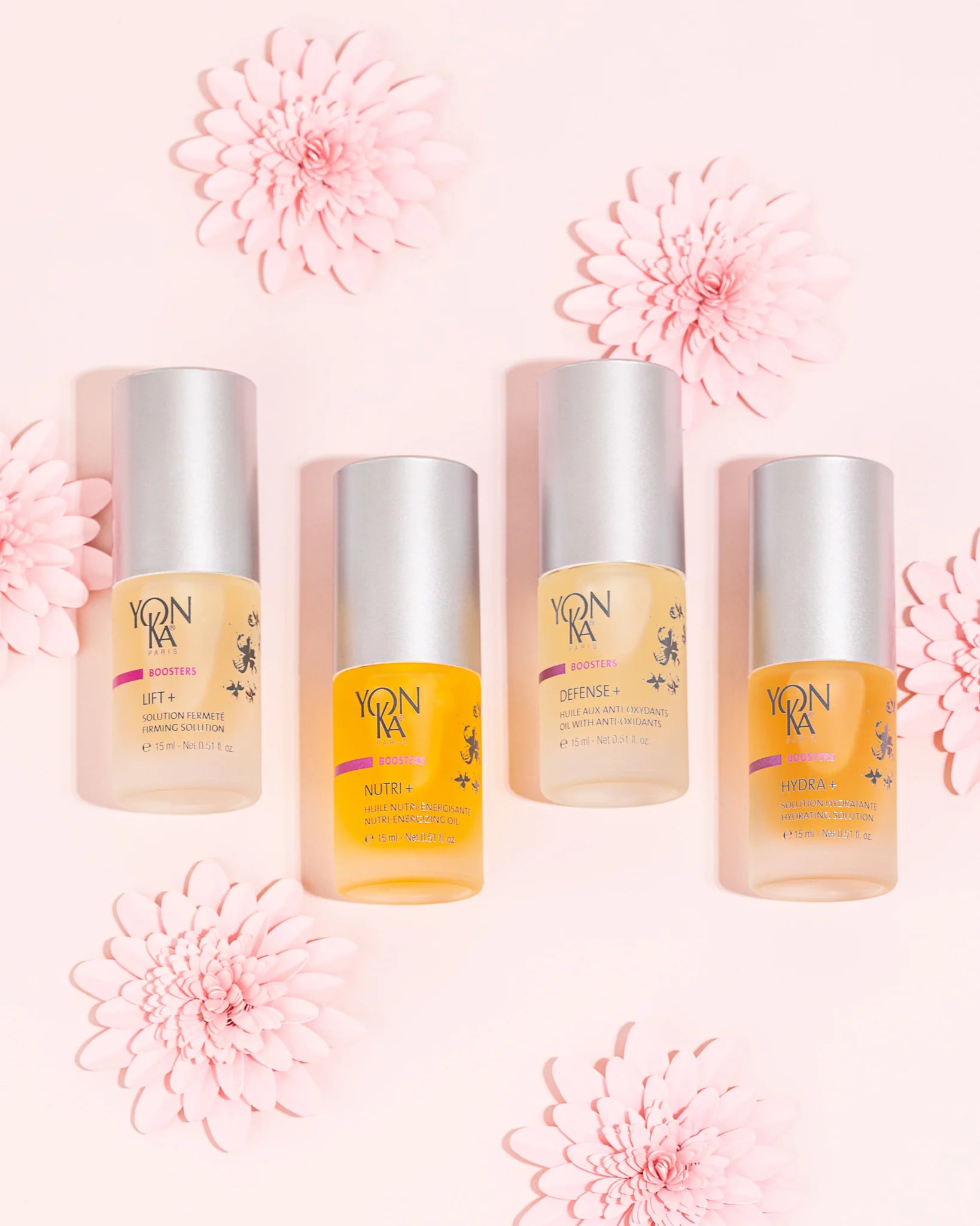 Four skincare bottles with a pink floral background