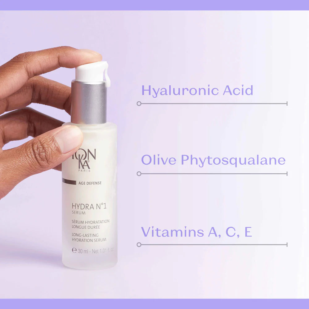 Skincare serum bottle held by a hand with text highlighting ingredients on a light purple background